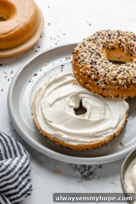 A close-up shot of creamy vegan cream cheese spread generously on a toasted bagel half, highlighting its smooth texture.