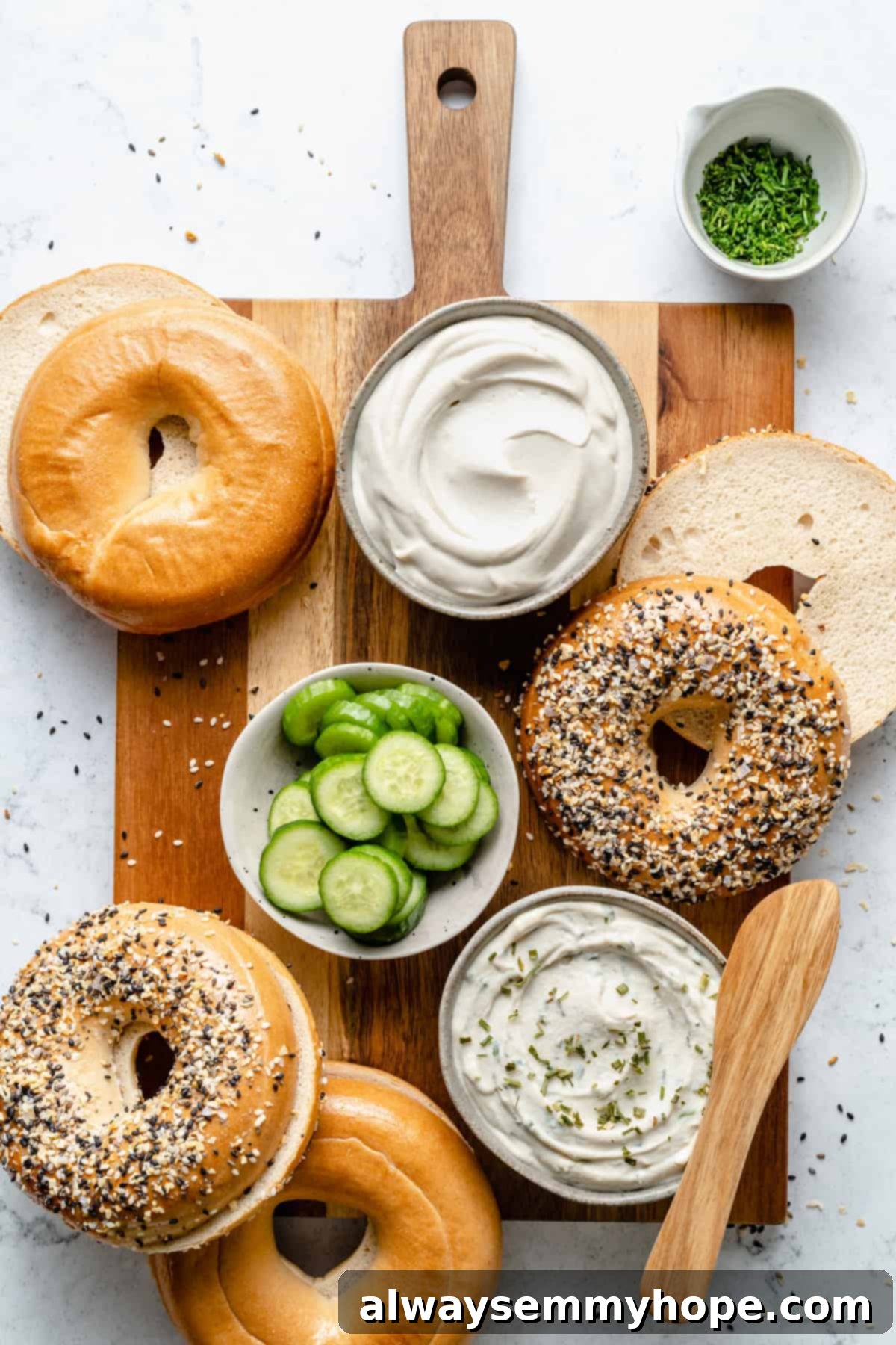Beautifully prepared bagels with generous amounts of homemade vegan cream cheese, topped with fresh cucumber slices, arranged on a serving board.