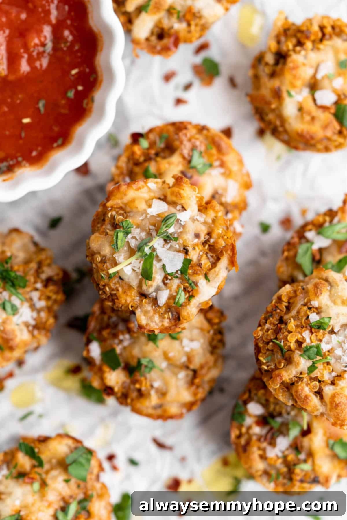 These Cheesy Vegan Quinoa Pizza Bites are packed with protein, incredibly delicious, and ideal for meal prep or parties. Stack of vegan quinoa pizza bites garnished with fresh herbs and a sprinkle of sea salt