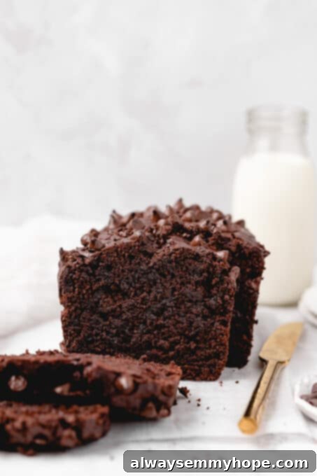 Fudgy Vegan Chocolate Banana Bread 16 A beautiful loaf of chocolate banana bread, partially cut into slices, on a wooden board.