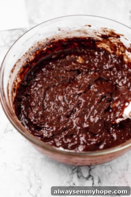 Fudgy Vegan Chocolate Banana Bread 8 Banana bread batter in a bowl with cocoa powder being sifted in.