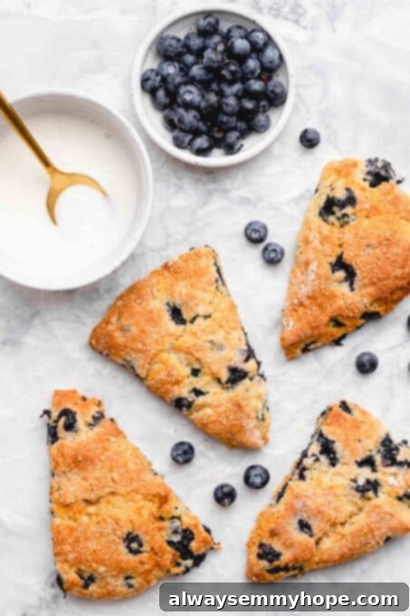 Fluffy Vegan Scones 13 Baked blueberry vegan scones with a bowl of lemon glaze and fresh blueberries on the side