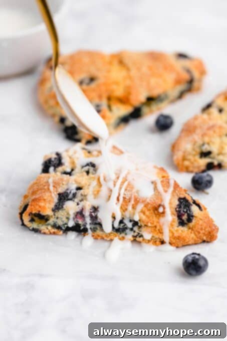 Fluffy Vegan Scones 14 White lemon glaze being generously drizzled over a warm blueberry vegan scone