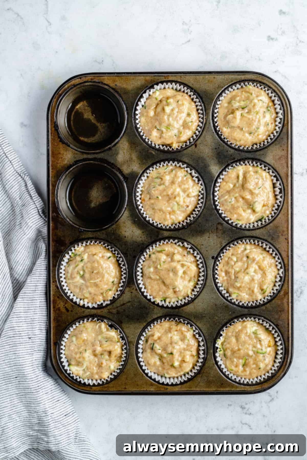 Garden-Fresh Vegan Zucchini Muffins 12 Zucchini muffin batter scooped into a muffin pan, ready for baking.