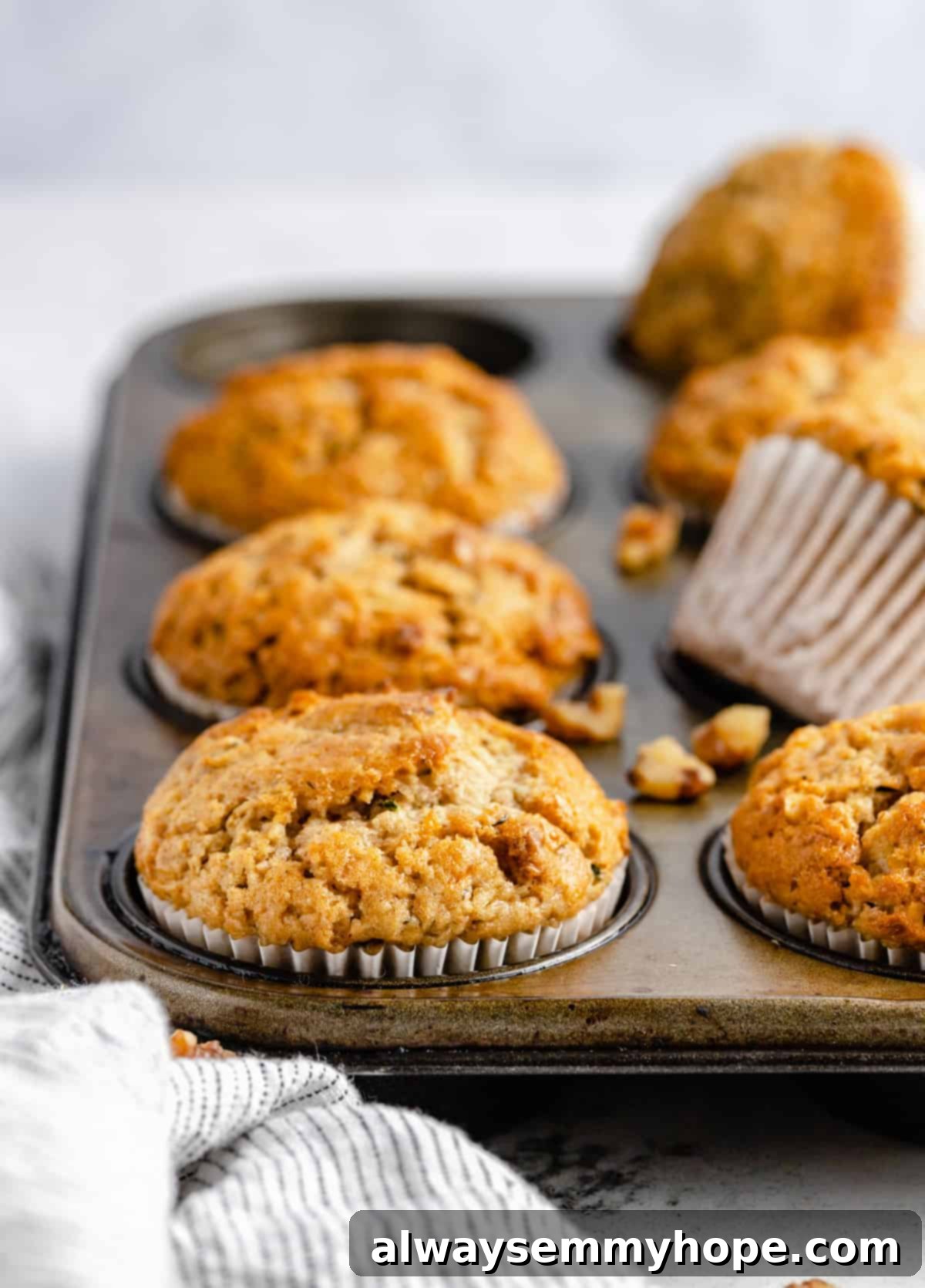 Garden-Fresh Vegan Zucchini Muffins 3 Freshly baked vegan zucchini muffins in a muffin pan, golden brown and perfectly risen.