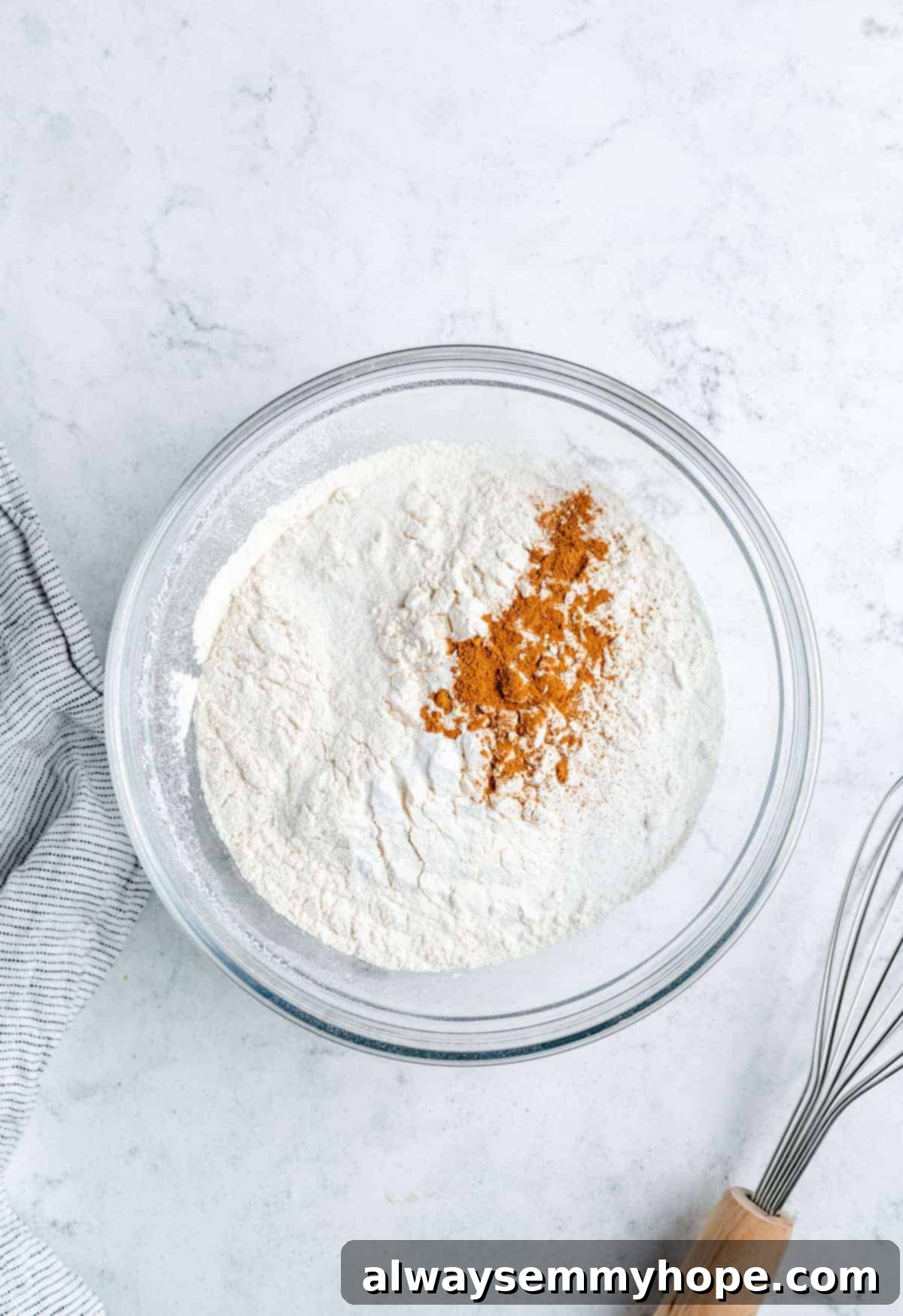 Ultimate Vegan Blueberry Muffins 10 A bowl containing the dry ingredients for blueberry muffins: flour, baking powder, salt, and cinnamon, perfectly mixed.