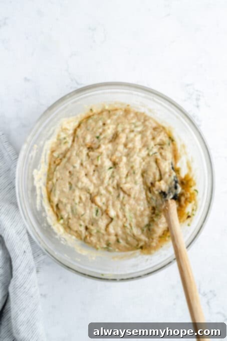 Vegan zucchini bread batter in a bowl, being scooped into the pan.
