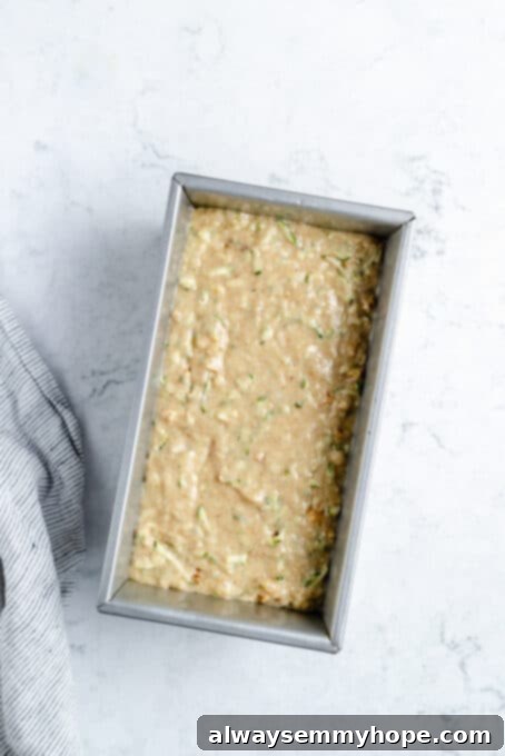Zucchini bread batter evenly spread in a loaf pan, ready for the oven.