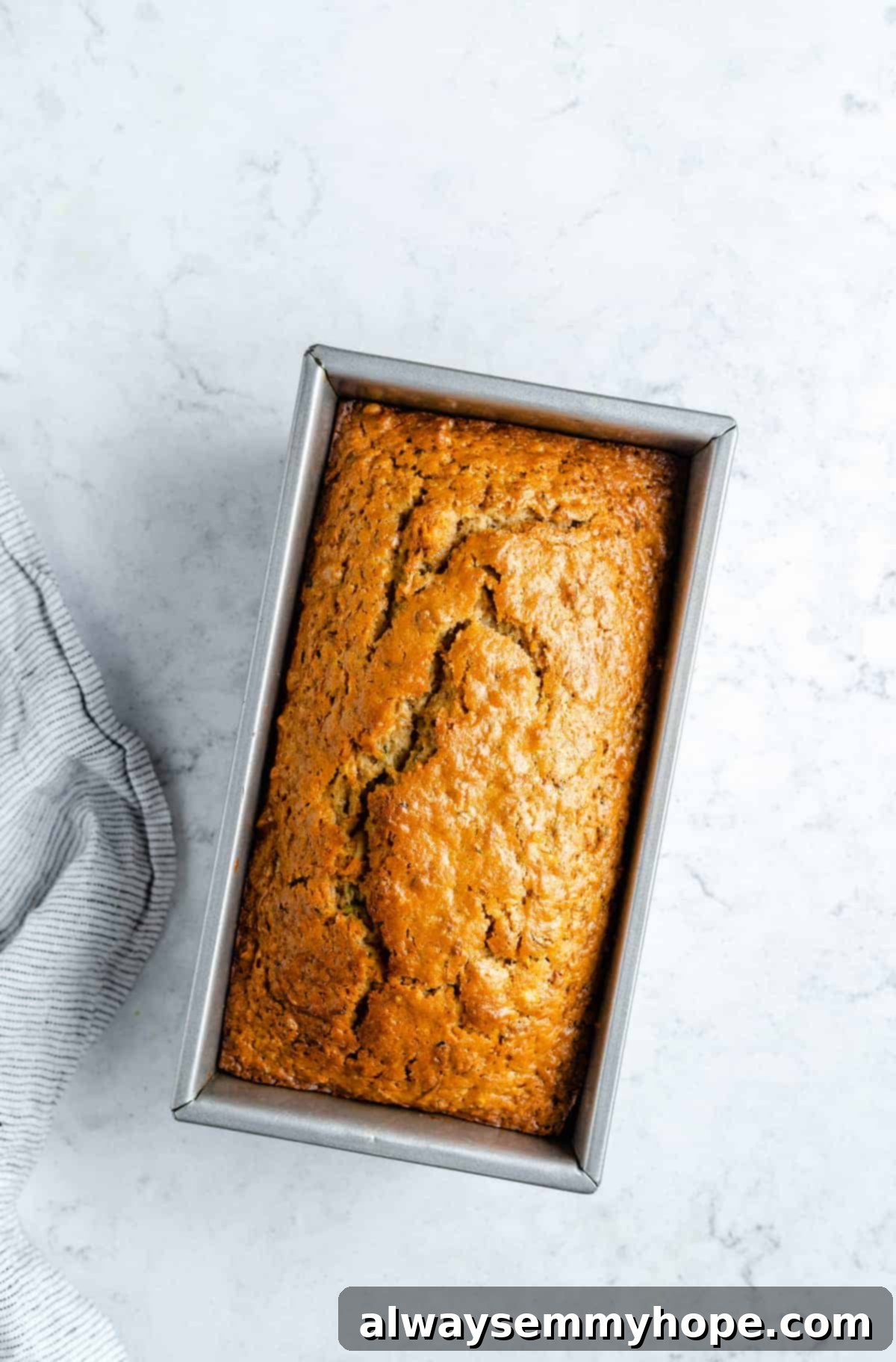 A freshly baked loaf of zucchini bread cooling in its loaf pan.