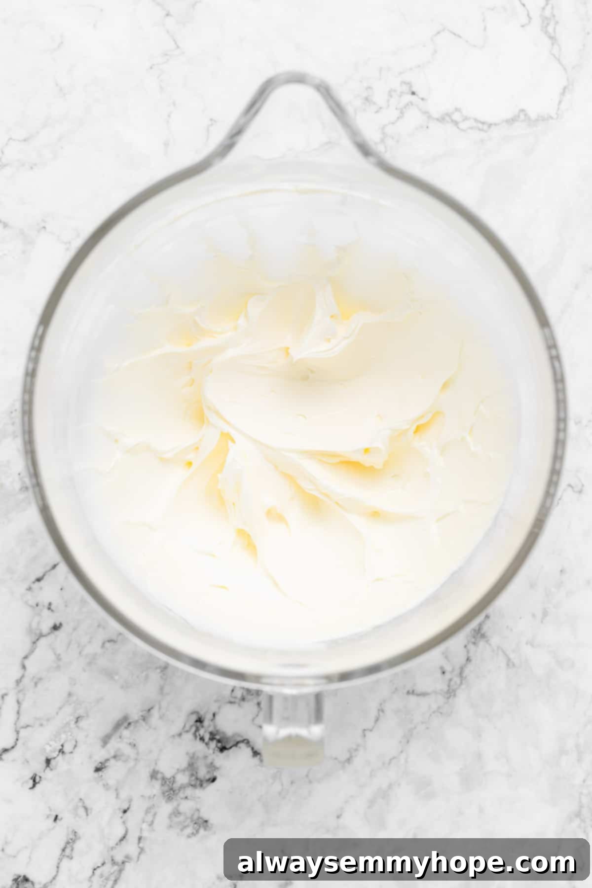 Whipped vegan butter and vanilla extract in a mixing bowl, fluffy and pale.