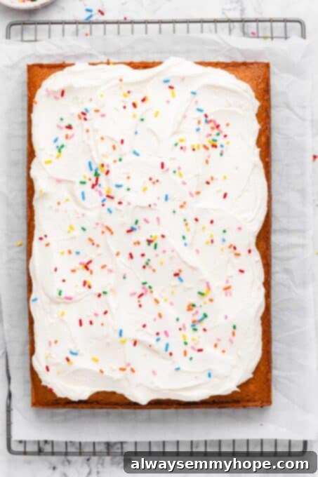 A beautifully frosted vegan vanilla sheet cake, adorned with colorful rainbow sprinkles.