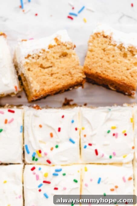 Several neat squares of vegan vanilla sheet cake with generous frosting on a white platter.