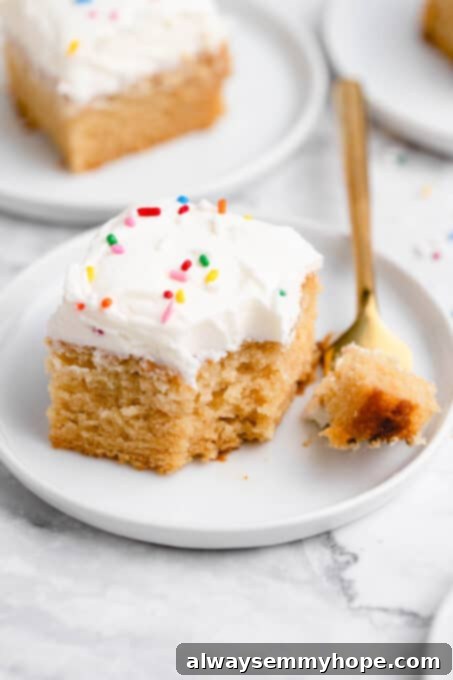 A delicious piece of vanilla sheet cake with a bite taken out, showing the fluffy texture.