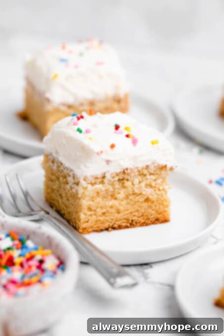 A slice of vegan vanilla sheet cake on a plate, topped with generous whipped buttercream frosting.