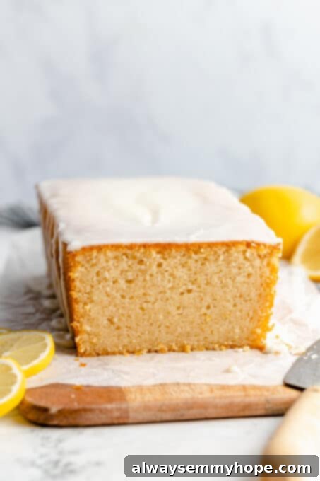 A full vegan lemon loaf cake generously coated with lemon-vanilla glaze, ready for serving.