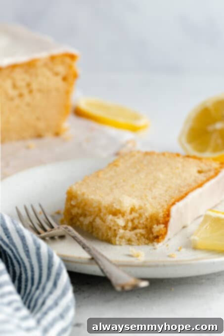 A delectable slice of vegan lemon loaf cake with a fork, highlighting its soft texture and inviting glaze.