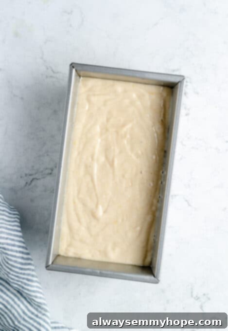 Smooth lemon loaf cake batter evenly distributed in a loaf pan, ready for the oven.