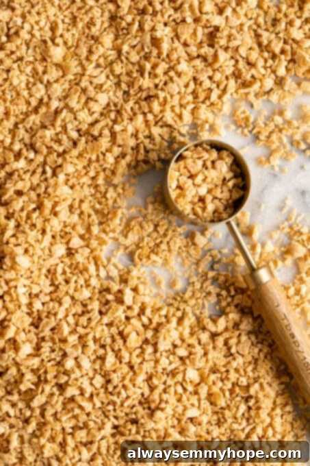 Dry Textured Vegetable Protein (TVP) granules resting on a wooden board, next to a measuring cup, ready for preparation. TVP is a highly versatile and protein-rich vegan meat substitute, commonly used to mimic ground meat in various dishes.