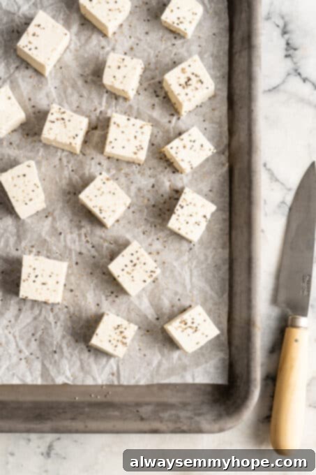 Perfectly seasoned tofu cubes laid out on a parchment-lined baking sheet, ready for baking or roasting. The image suggests a meal is being prepared, showcasing tofu's versatility as a plant-based protein source.