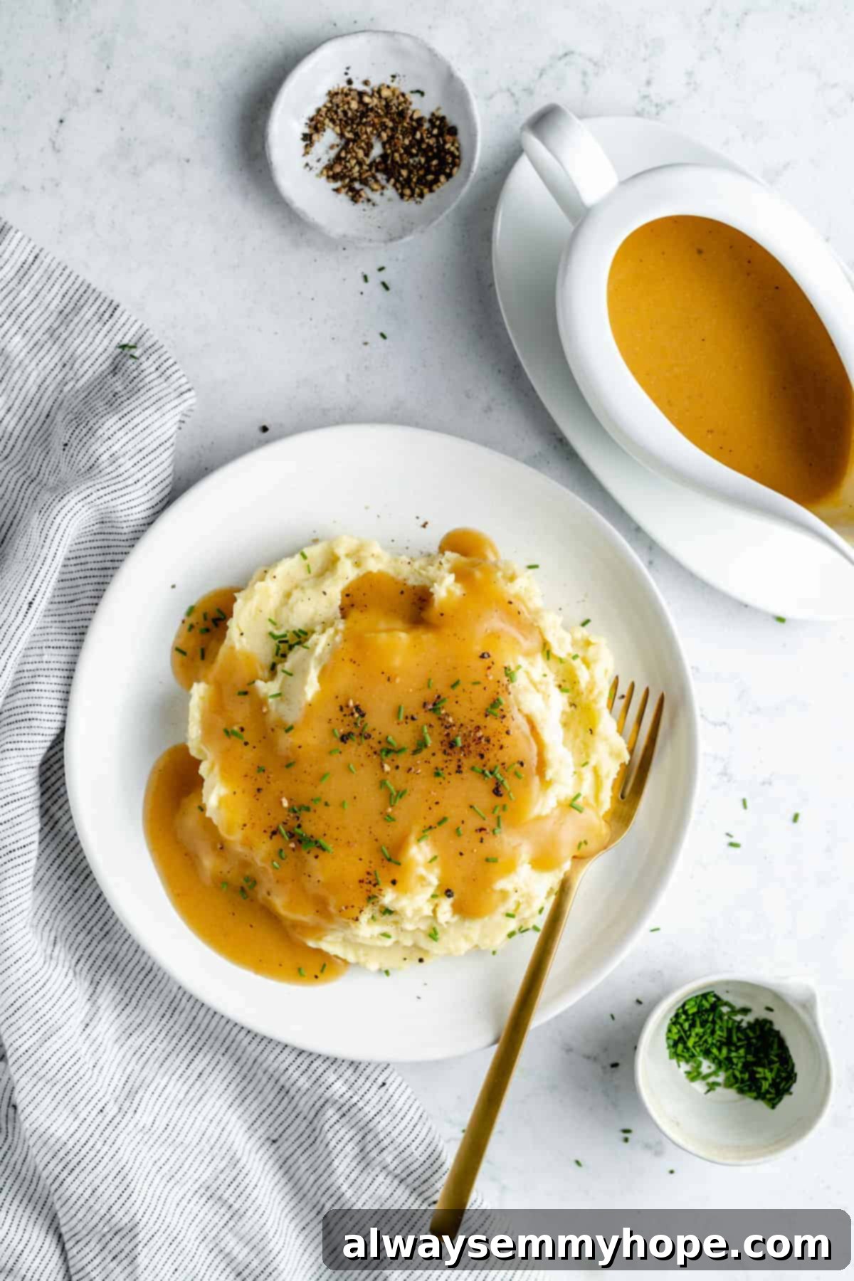 This vegan gravy is easy to make, silky smooth, and delicious over mashed potatoes! It's packed with savoury flavour, made without mushrooms. Overhead shot of creamy mashed potatoes on a white plate generously topped with rich vegan gravy, garnished lightly with fresh herbs.