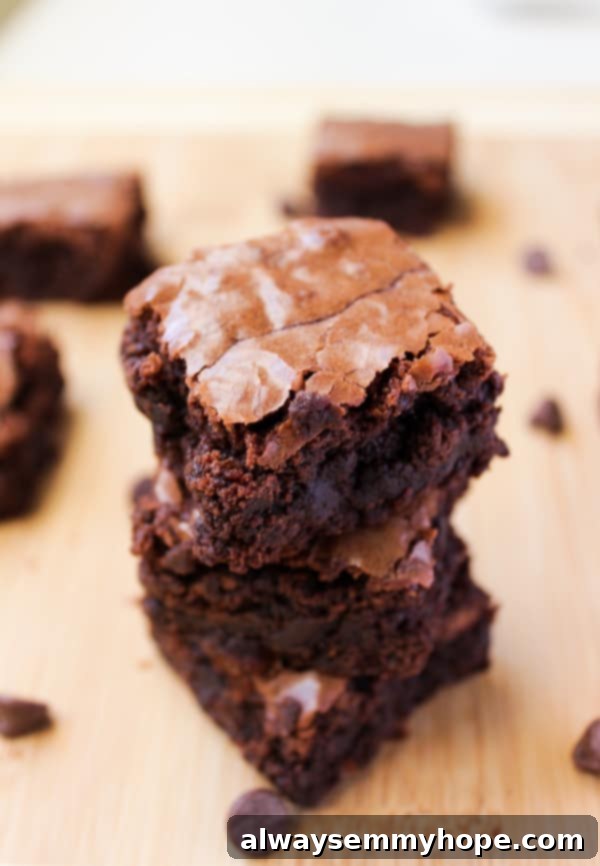 A stack of perfectly cut chewy brownies, showcasing their rich, fudgy texture and melted chocolate chips.