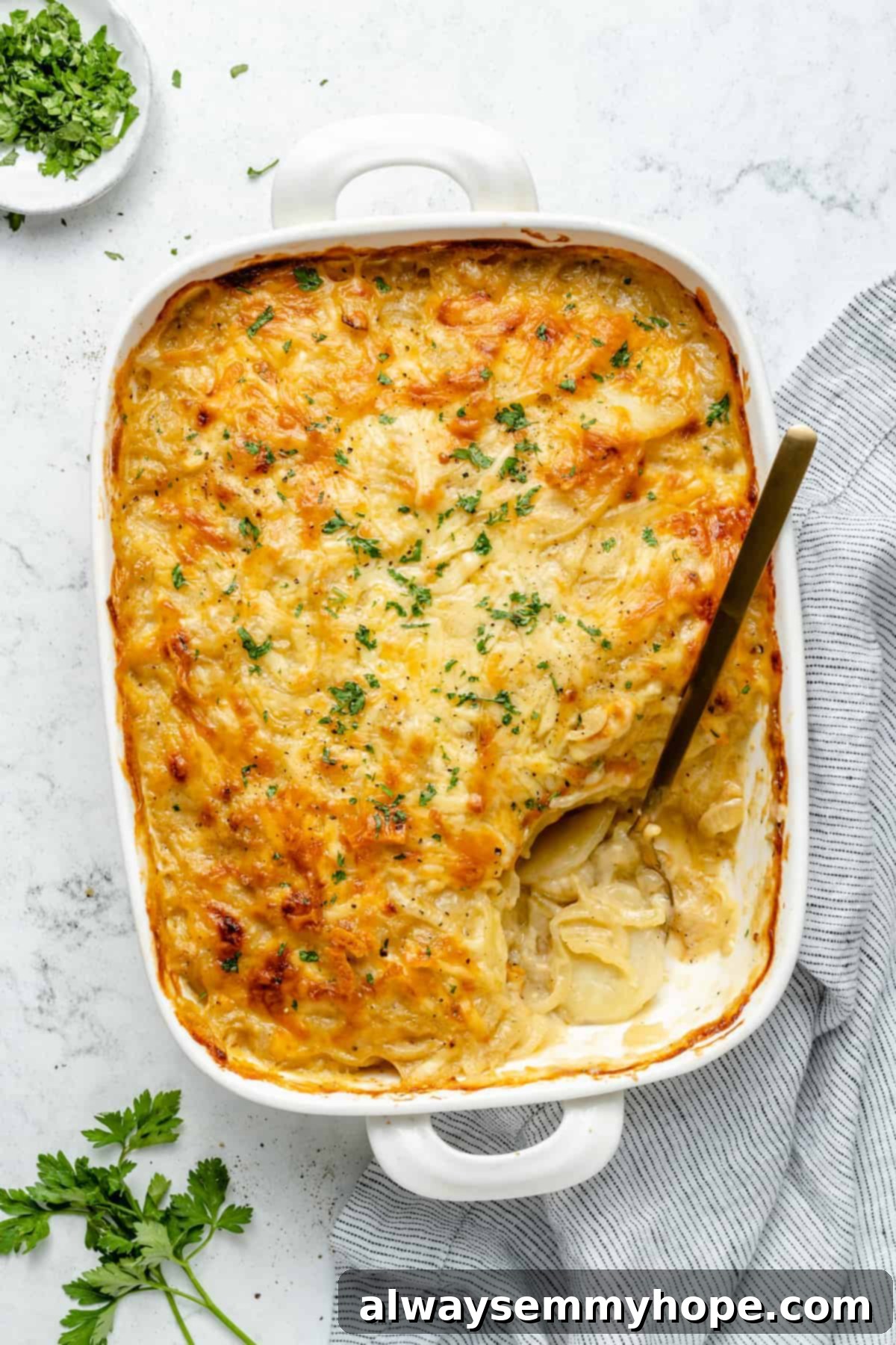 My creamy vegan scalloped potatoes are dairy-free, cheesy, and easy to make! The perfect side dish for Thanksgiving, holidays, and weeknights. Overhead view of scalloped potatoes in baking dish with a serving scooped out