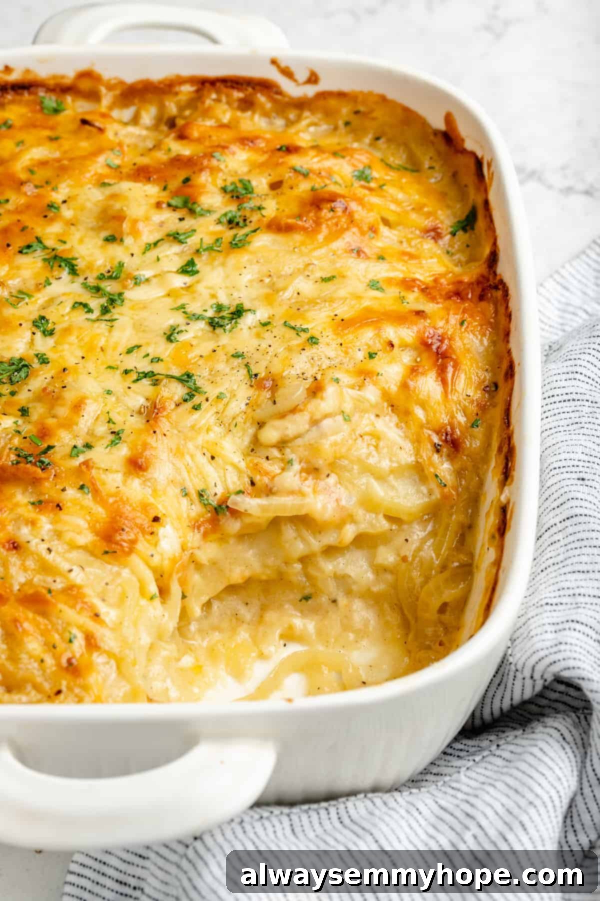 My creamy vegan scalloped potatoes are dairy-free, cheesy, and easy to make! The perfect side dish for Thanksgiving, holidays, and weeknights. Vegan scalloped potatoes in white baking dish with serving removed