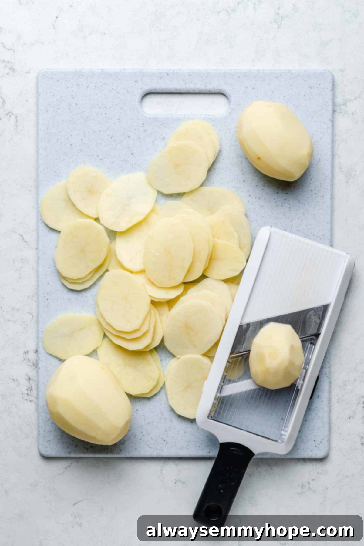 My creamy vegan scalloped potatoes are dairy-free, cheesy, and easy to make! The perfect side dish for Thanksgiving, holidays, and weeknights. Overhead view of potatoes being sliced with mandoline slicer