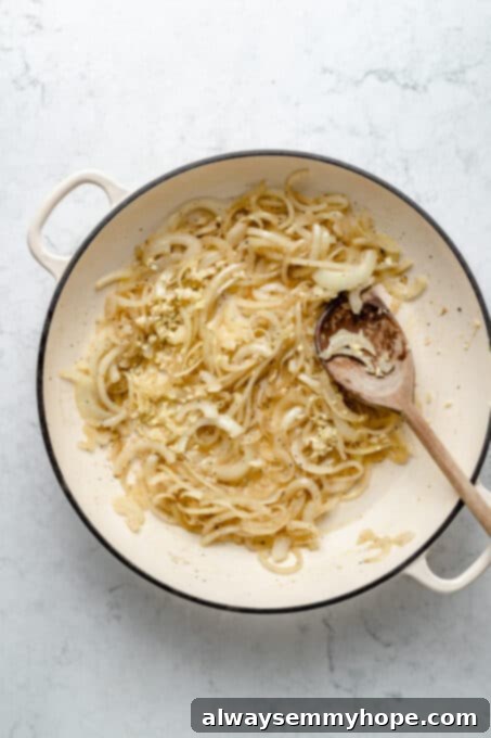 My creamy vegan scalloped potatoes are dairy-free, cheesy, and easy to make! The perfect side dish for Thanksgiving, holidays, and weeknights. Cooking onions in saucepan with wooden spoon