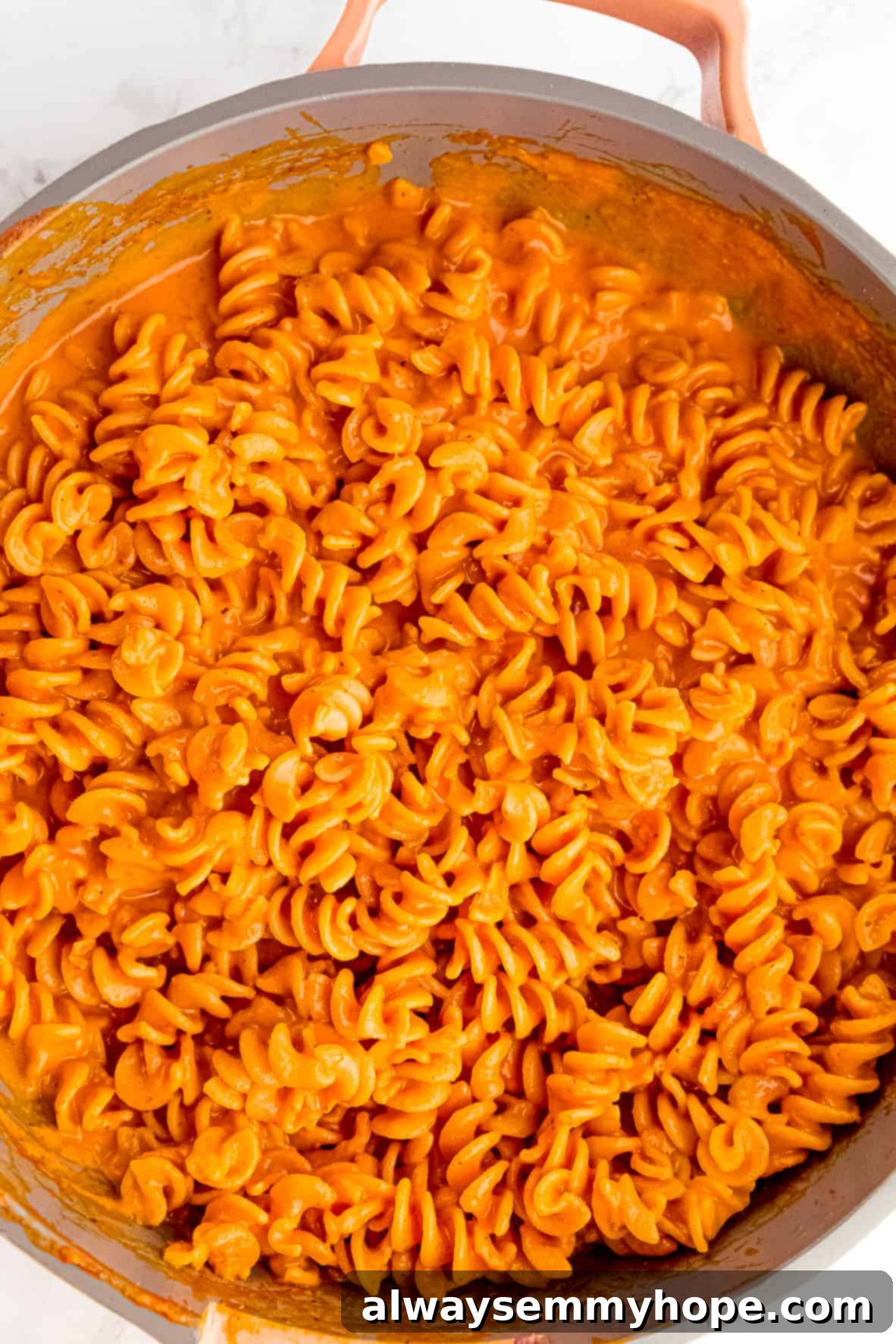 Overhead view of roasted red pepper pasta in a large skillet.