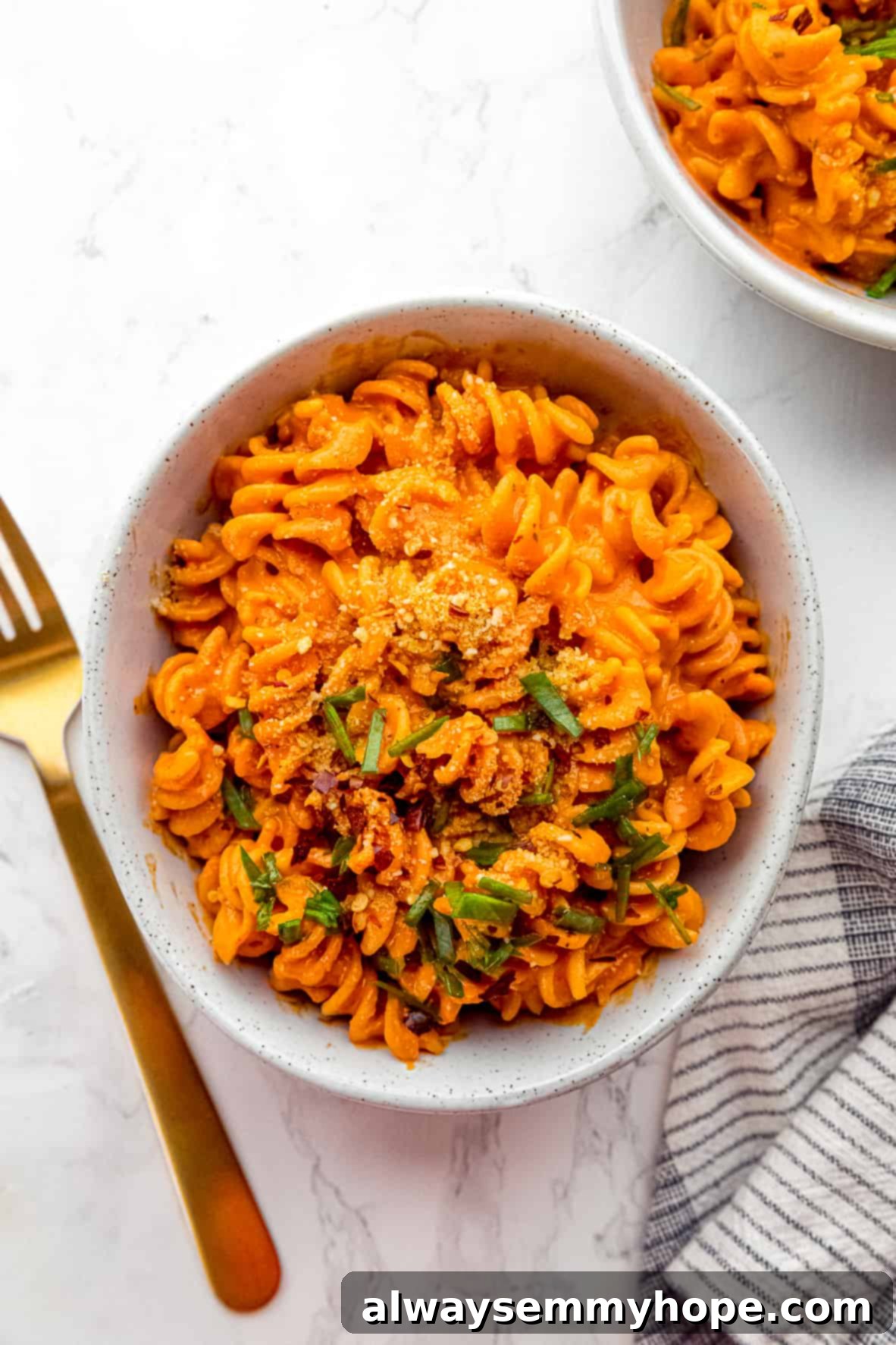 Overhead view of roasted red pepper pasta in a bowl next to a fork.