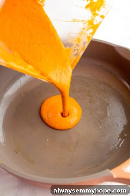 Pouring red pepper pasta sauce into a skillet.