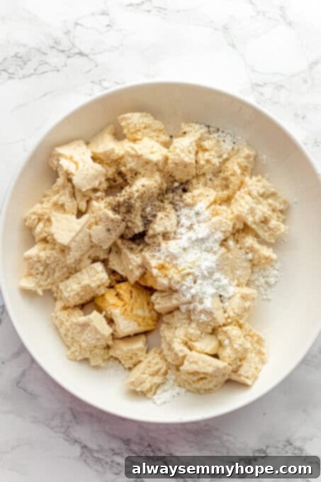 Korean Gochujang Tofu Rice Bowls 9 Torn tofu pieces in a bowl with soy sauce, sea salt, black pepper, and cornstarch sprinkled on top.