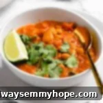Close-up of a vibrant and creamy coconut chickpea curry, garnished with fresh herbs, in a serving bowl.