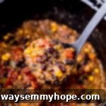 A ladle spooning a generous portion of rich and chunky vegan chili out of a slow cooker, illustrating its hearty texture.