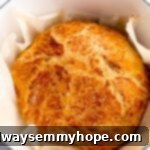 A beautifully baked round of no-knead bread in a Dutch Oven, viewed from above, showcasing its rustic, golden-brown crust.