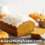 A beautifully baked loaf of pumpkin bread generously topped with a thick, swirling layer of cream cheese frosting, perfect for a sweet fall treat.
