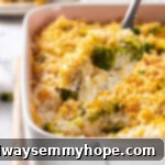 A serving spoon lifting a golden portion of vegan broccoli cheese rice casserole from a rustic baking dish, showcasing its creamy texture.