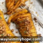 Overhead view of a beautifully fanned hasselback butternut squash, perfectly roasted, with a fork poised to serve.