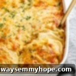 Creamy vegan scalloped potatoes baked to golden perfection in a baking dish, with a spoon scooping out a generous, layered serving.