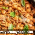 Overhead view of creamy tomato pasta served in a skillet, garnished generously with fresh basil leaves, showcasing its vibrant color and appealing texture.