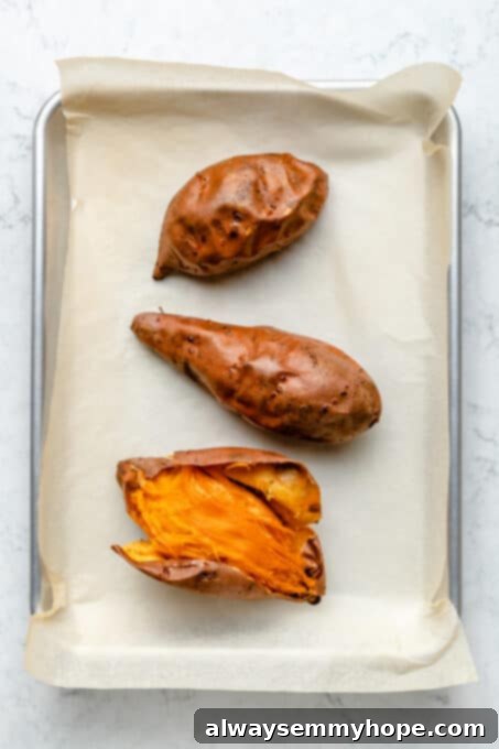 This creamy vegan sweet potato pie is easy to make with coconut milk and warm spices. It's dairy-free, egg-free, and great for Thanksgiving! Freshly roasted sweet potatoes, glistening and tender, resting on a baking sheet lined with parchment paper, their skins slightly caramelized.