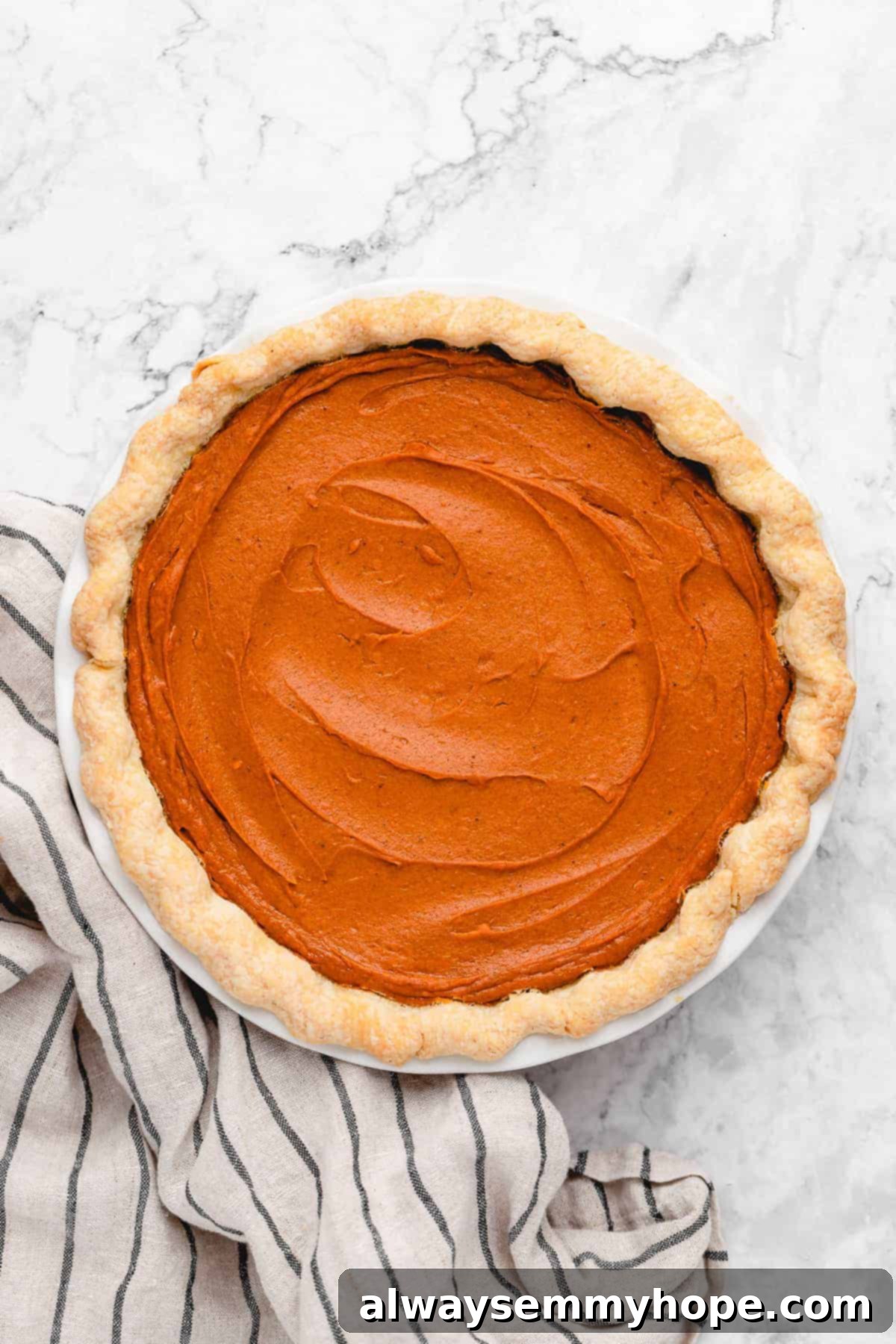 This creamy vegan sweet potato pie is easy to make with coconut milk and warm spices. It's dairy-free, egg-free, and great for Thanksgiving! An inviting overhead view of a beautifully baked vegan sweet potato pie, featuring a golden-brown, flaky crust and a perfectly smooth, rich filling.