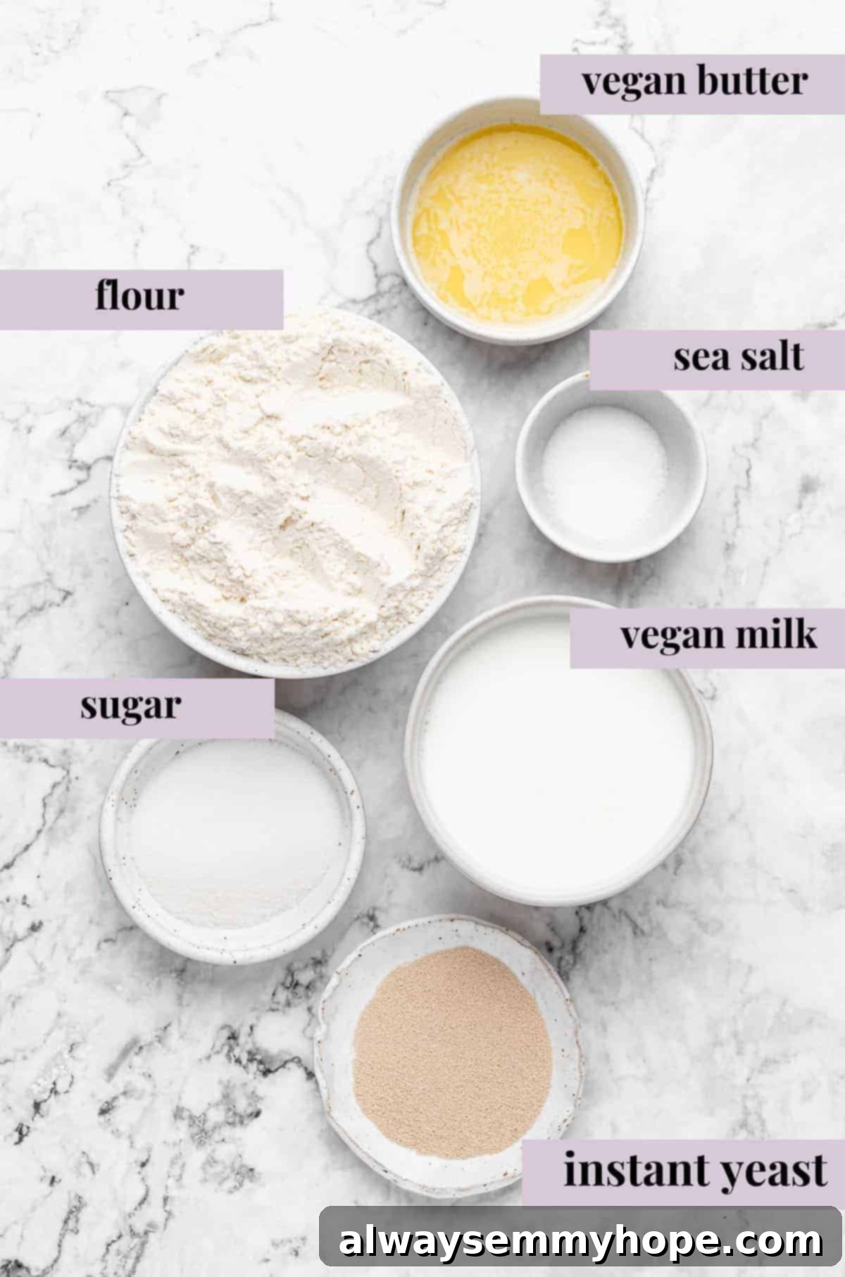 A flat lay photograph displaying the ingredients for vegan dinner rolls, clearly labeled on a clean surface.
