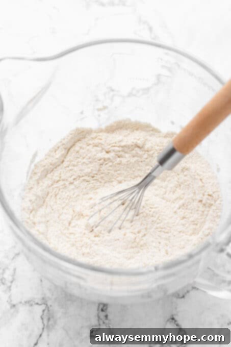 Dry ingredients for vegan dinner rolls stirred together in a bowl, creating a uniform mixture.