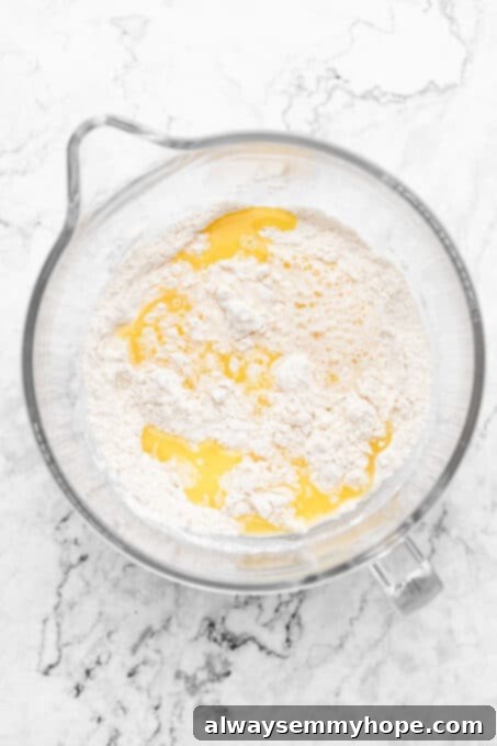 Melted vegan butter being poured over the dry ingredients in a bowl, preparing for mixing.