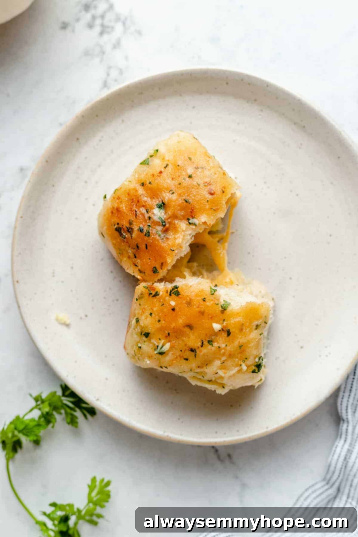Fluffy Vegan Garlic Parmesan Dinner Rolls 15 Two garlic parmesan dinner rolls on a plate pulled apart to show cheese inside