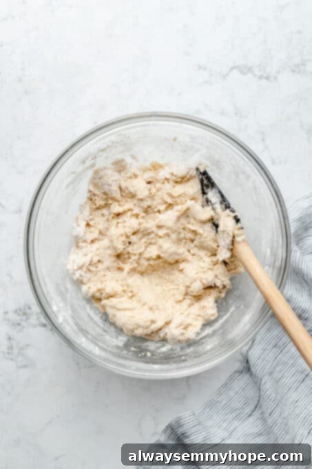 Fluffy Vegan Garlic Parmesan Dinner Rolls 6 Overhead view of dinner roll dough in glass mixing bowl with spatula