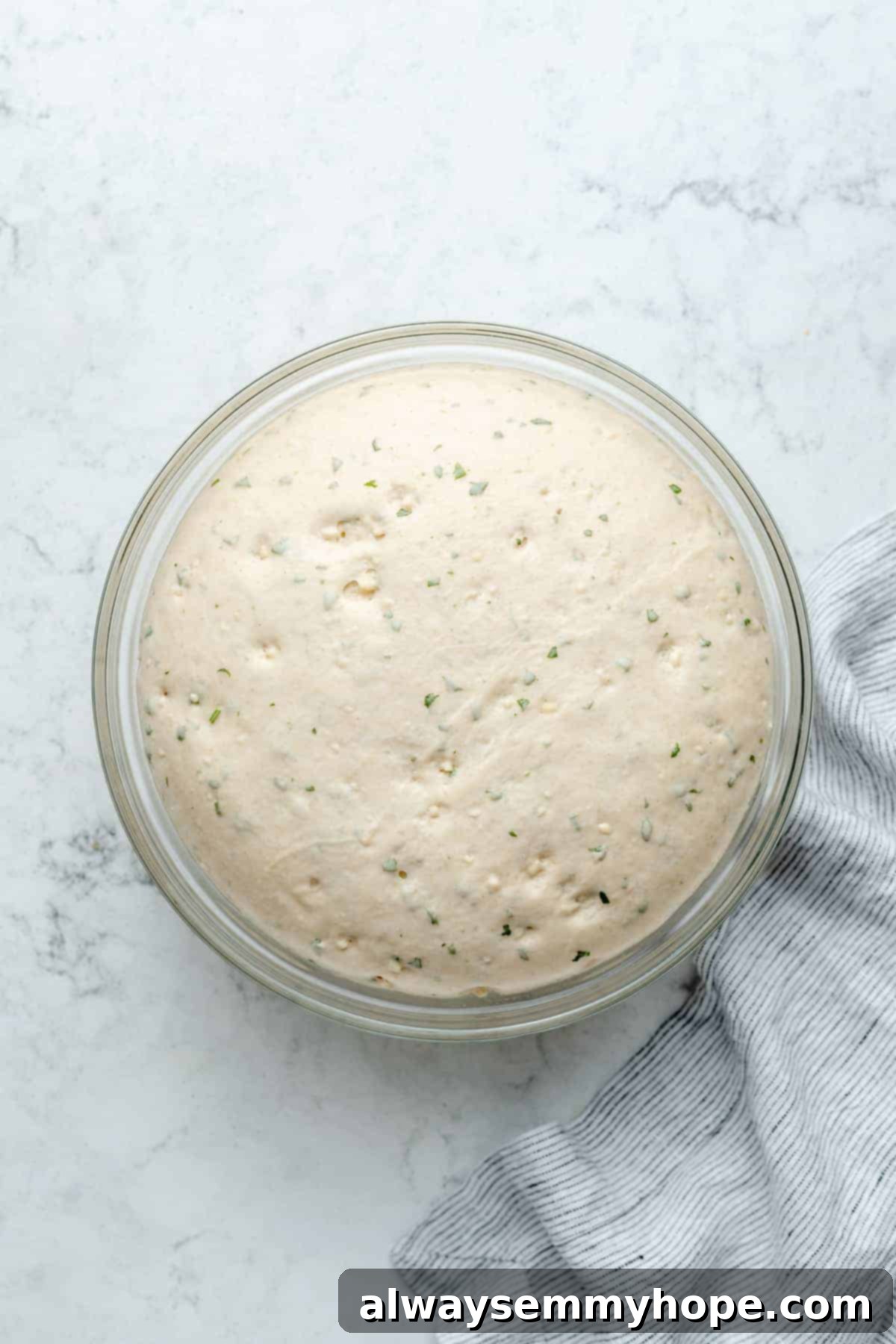 Fluffy Vegan Garlic Parmesan Dinner Rolls 9 Overhead view of dough in glass mixing bowl after rising