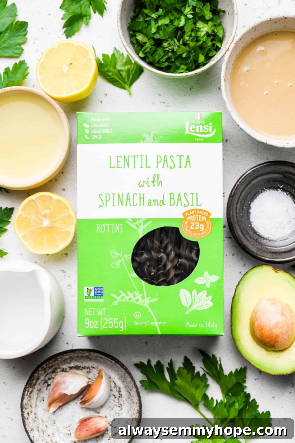 Divine Green Pasta 3 A vibrant selection of fresh ingredients including avocado, parsley, garlic, lemon, tahini, and a box of lentil pasta, ready for making green goddess pasta.